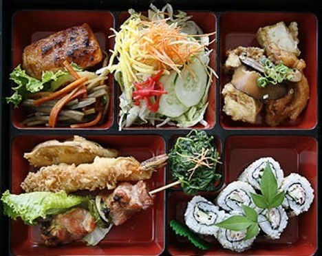 A Natsunoya bento in a red and black lacquered box: tempura, maki sushi, salad and grilled fish in separate compartments