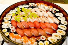 A large round platter of nigiri and maki sushi